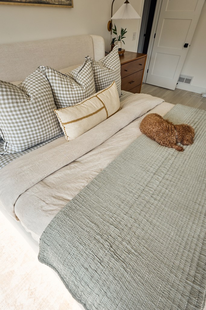 Close-up of gingham throw pillows on the bed with our dog curled up in the cozy fall bedroom refresh