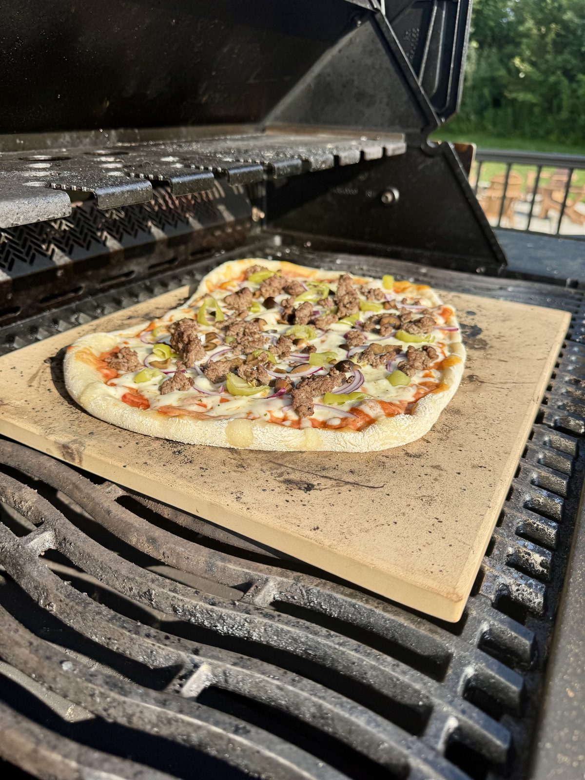Pizza cooking on a pizza stone on the grill